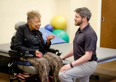 A woman in a motorized wheelchair works on rehab exercises